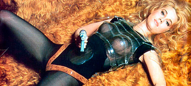 Barbarella (Jane Fonda) deitada e segurando uma arma laser