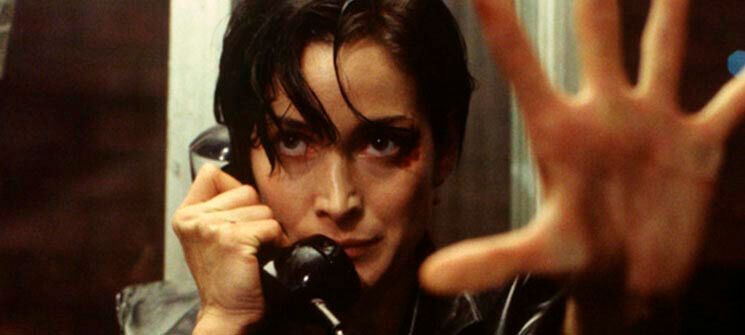 Trinity (Carrie-Anne Moss) segurando um telefone em Matrix