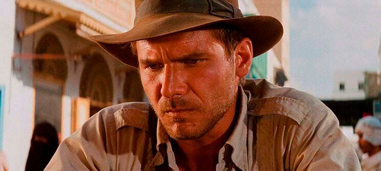 Indiana Jones interpretado por Harrison Ford pensativo em Os Caçadores da Arca Perdida. Um dos personagens mais famosos dos anos 80. 