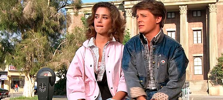 Claudia Wells e Michael J. Fox sentados em um banco em De Volta para o Futuro (1985)