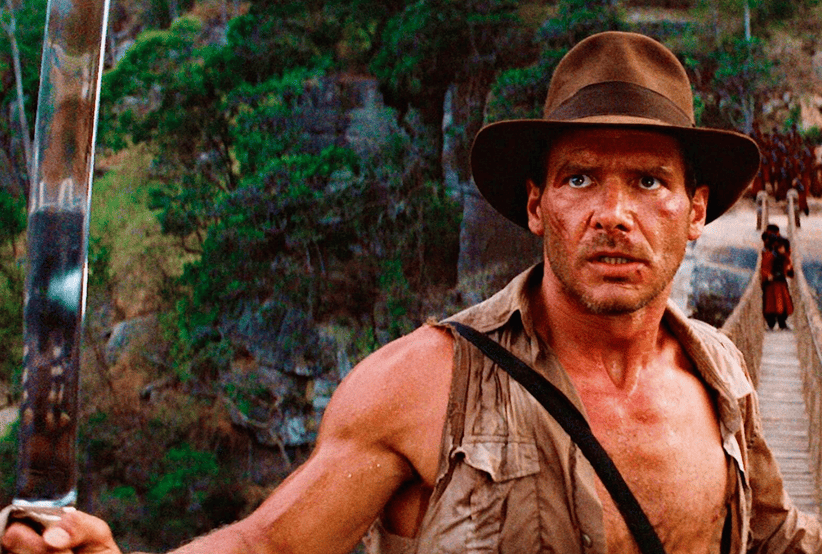 Indiana Jones interpretado por Harrison Ford pensativo em Os Caçadores da Arca Perdida. Um dos personagens mais famosos dos anos 80.