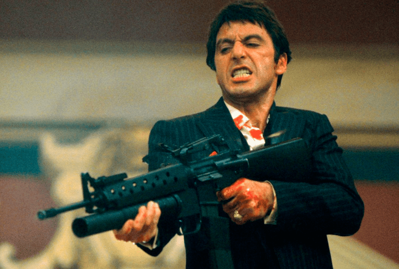 Tony Montana interpretado por Al Pacino segurando uma metralhadora em Scarface. Um dos personagens mais famosos dos anos 80.