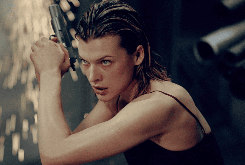 Alice (Milla Jovovich) segurando uma pistola em Resident Evil. 30 personagens femininas que marcaram a história do cinema