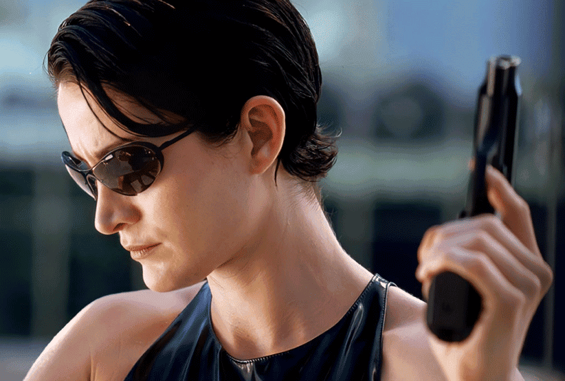 Trinity (Carrie-Anne Moss) segurando um telefone em Matrix. 30 personagens femininas que marcaram a história do cinema