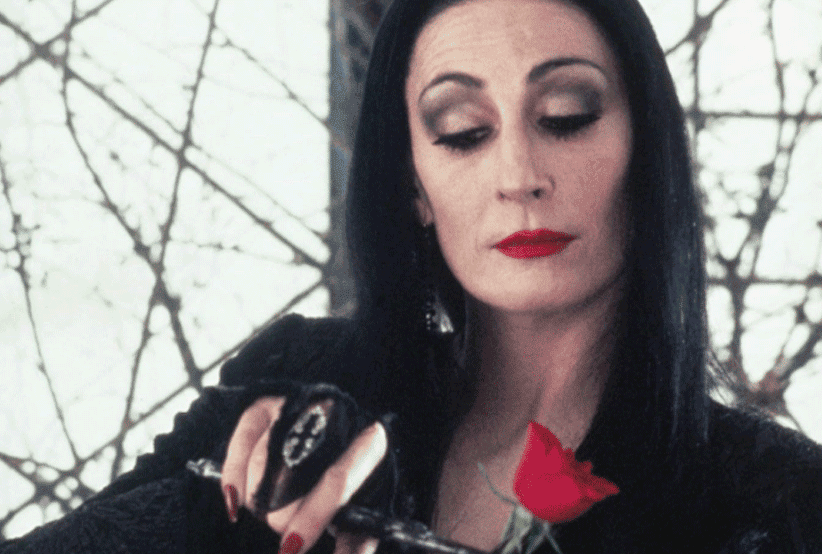 Morticia (Anjelica Huston) segurando um pé de cabra em A Família Addams. 30 personagens femininas que marcaram a história do cinema