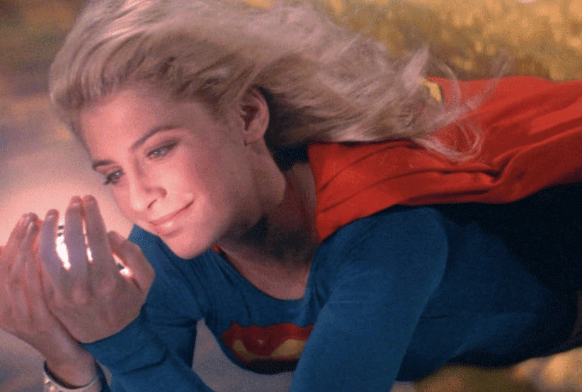 Supergirl (Helen Slater) voando e segurando um cristal. 30 personagens femininas que marcaram a história do cinema 