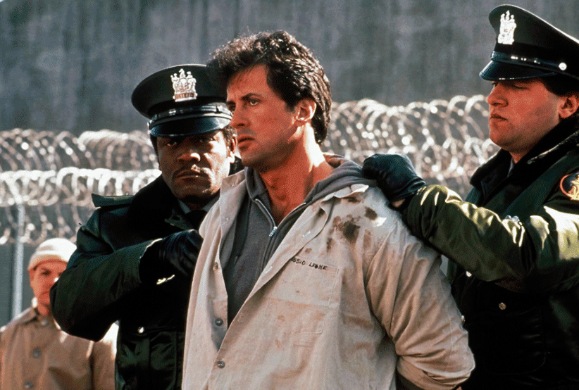 Frank (Sylvester Stallone) sendo guiado por guardas para cadeia