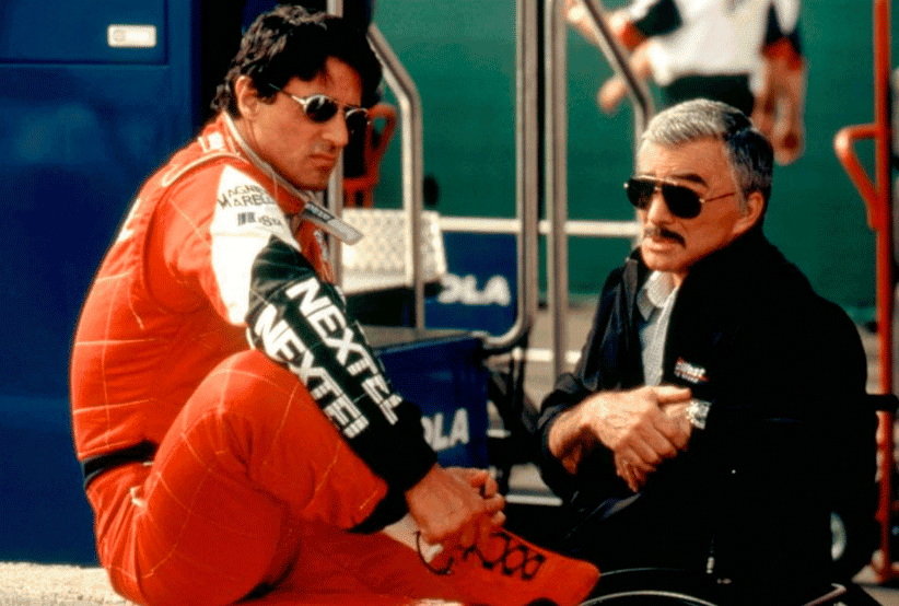 Jimmy (Sylvester Stallone) usando macacão de corrida ao lado de Henry (Burt Reynolds)