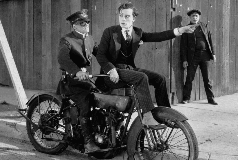 Buster Keaton com uma cartola, segurando uma lupa e lendo um livro; no filme Bancando o Águia, um dos clássicos em Efeitos especiais e visuais.