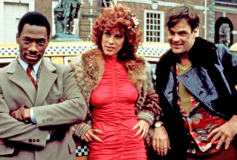 (Dan Aykroyd), Eddie Murphy e Jamie Lee Curtis no filme Trocando as Bolas (1983). Em uma lista dos melhores filmes de natal.