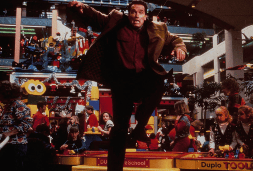 Howard Langston (Arnold Schwarzenegger) no filme Um Herói de Brinquedo (1996). Em uma lista dos melhores filmes de natal.