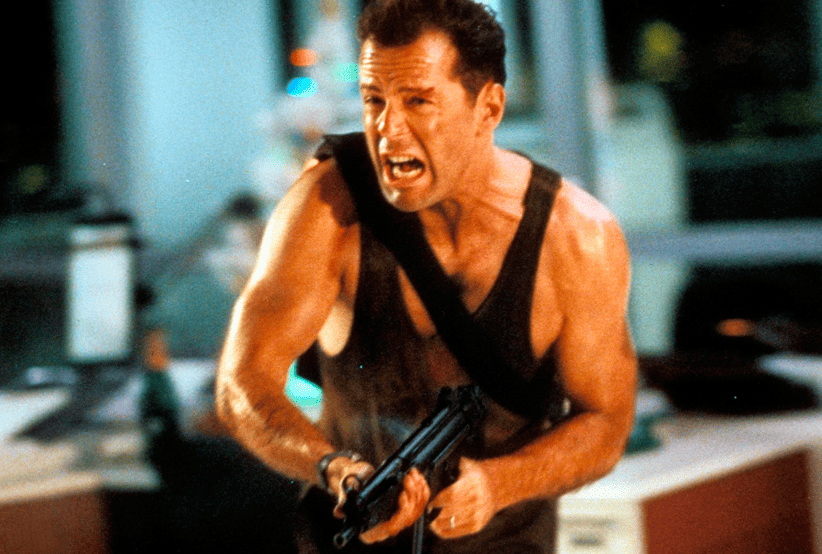 John McClane (Bruce Willis) no filme Duro de Matar (1988). Em uma lista dos melhores filmes de natal.